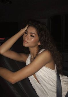 a woman sitting in the back seat of a car with her hand on her head