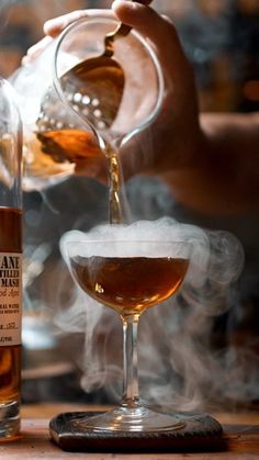 a person pours a drink into a glass with steam rising from the top and bottom