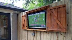 a flat screen tv mounted to the side of a wooden fence