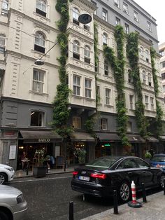 cars are parked on the street in front of an old building with ivy growing all over it