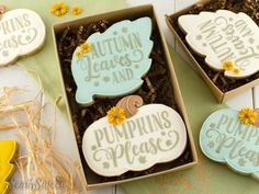 two decorated cookies in a box with autumn leaves and pumpkins written on the top