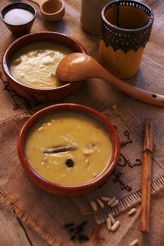 two bowls filled with soup on top of a table next to wooden spoons and cinnamon sticks