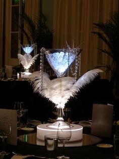 two martini glasses with white feathers in front of them