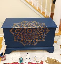 a blue box with gold designs on it sitting on the ground next to some paint