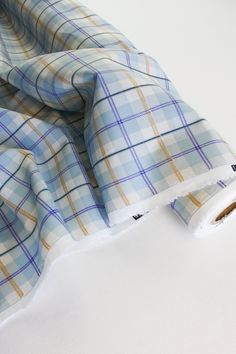 a blue and yellow checkered shirt laying on top of a white tablecloth with torn edges