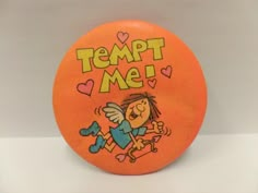 an orange frisbee with the words tempt me on it and a cartoon character