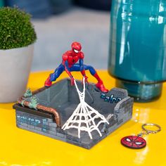 a spiderman figurine is sitting on a table next to a keychain