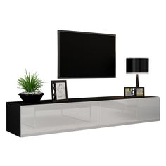 an entertainment center with a flat screen tv mounted on it's sideboard and a potted plant next to it