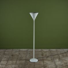 a white floor lamp sitting on top of a wooden floor next to a green wall