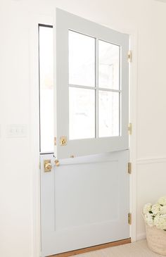 a white door with a basket of flowers on the floor