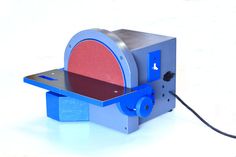 a small machine with a red disc on it's back end and blue wheels