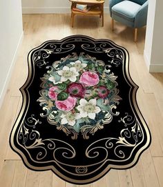 a black area rug with pink and white flowers in the center on a wooden floor