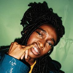 a woman with dreadlocks is posing for the camera while wearing a blue jacket