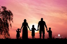 a family silhouetted against the sunset with their hands in each other's pockets