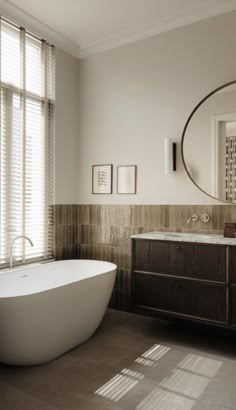 a bath tub sitting next to a bathroom sink under a round mirror in a bathroom