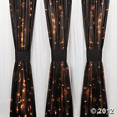 three curtains with lights on them in front of a window