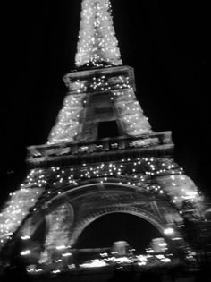 the eiffel tower is lit up at night with christmas lights all around it