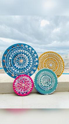 four colorful plates sitting on top of a window sill in front of a cityscape