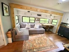 a living room filled with furniture and a large rug on top of a hard wood floor