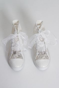 two pairs of white shoes with bows and laces on the bottom one shoe has an embellishment that says mum