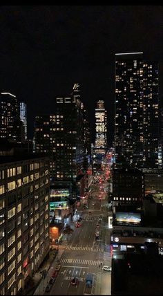 the city skyline is lit up at night with cars driving down it's street