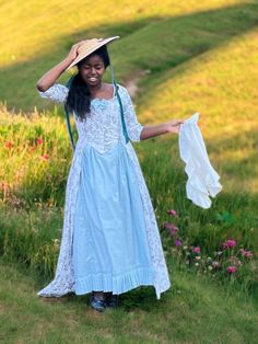 a woman in a blue dress and hat is holding a white shirt over her head