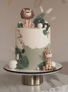 there is a cake decorated with animals on the top and bottom, along with greenery