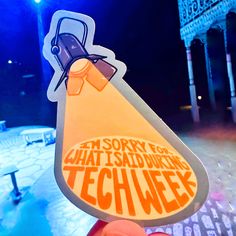 someone holding up a sticker that says tech week in front of a stage with lights