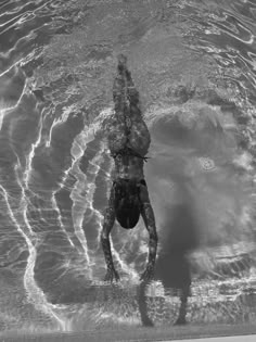 a man swimming in the water with his back turned to the camera and arms outstretched