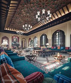 an ornately decorated living room with blue couches and chandelier hanging from the ceiling