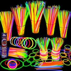 glow sticks and neon bracelets are arranged on a black background with an assortment of colors