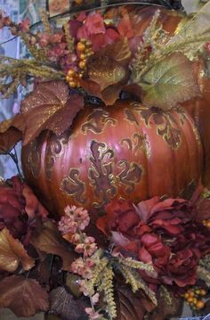 a decorative pumpkin sitting on top of a pile of leaves