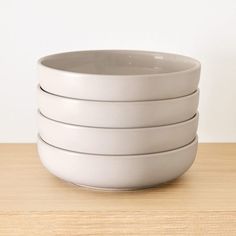 a stack of white bowls sitting on top of a wooden table