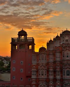 the sun is setting behind an ornate building