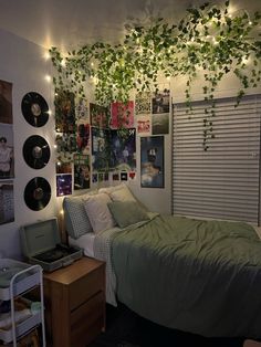 a dorm room with plants growing on the ceiling and vinyl records hanging from the wall