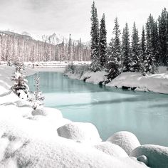 a river surrounded by snow covered mountains and trees