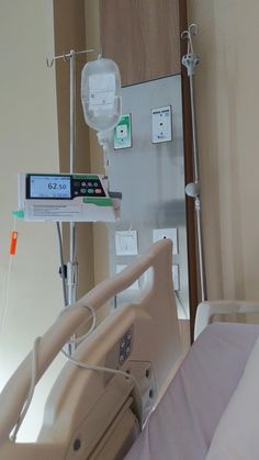 a hospital bed with an electronic monitor on the wall and medical equipment in the background