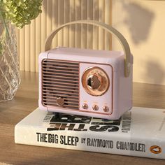 a pink radio sitting on top of a book next to a vase filled with flowers