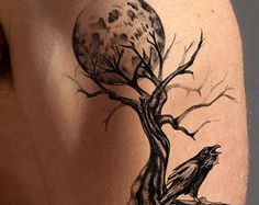 a man's back with a tree and moon tattoo on his left side shoulder