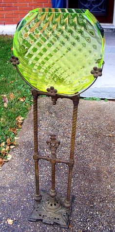 a green glass dish sitting on top of a metal stand in front of a brick building