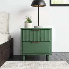 a green nightstand next to a bed in a room with white walls and wooden floors