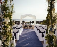 an outdoor ceremony set up with white and blue linens on the aisle, decorated with flowers