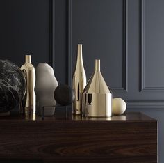 some vases are sitting on top of a wooden table in front of a black wall