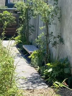 a wooden bench sitting in the middle of a garden next to a tall white building