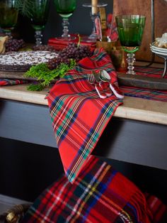 the table is set with plaid napkins and green wine glasses on top of it