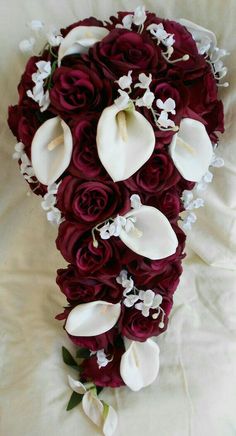 a bridal bouquet with white calla lilies and orchids on a bed