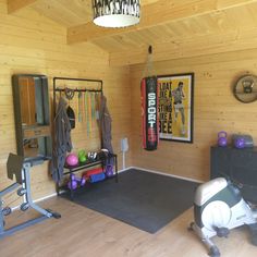 a home gym with exercise equipment and wall hangings on the walls, in a wood paneled room