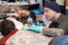 a man getting his tattoo done by a woman