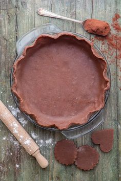 a chocolate pie sitting on top of a wooden table next to other baking utensils