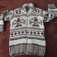 a sweater with an animal pattern on it laying on a brown surface next to a pair of scissors